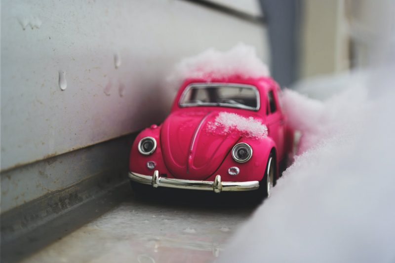 red volkswagen beetle die cast metal model beside white wall