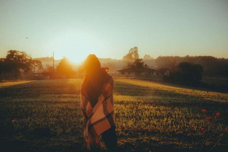 woman standing on a field at sunset