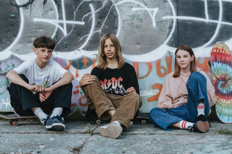 teenagers sitting on gray concrete pavement