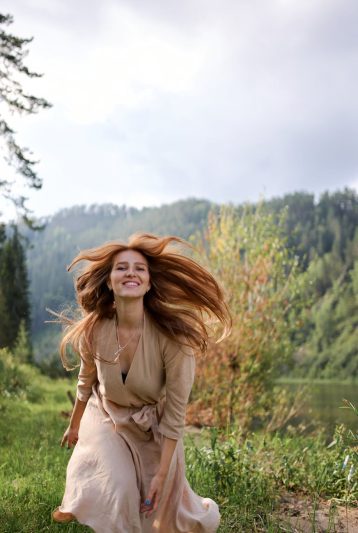 happy woman with flying hair on river coast