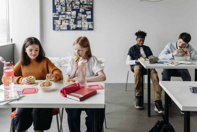 a girls and boys eating in the classroom