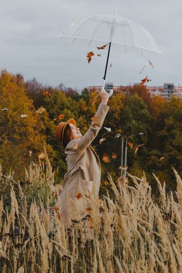 woman holding an umbrella on a field in autumn