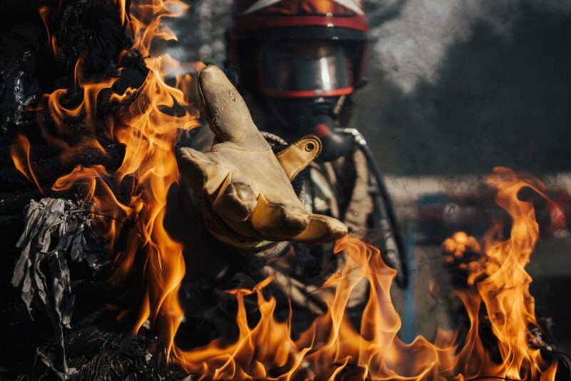 firefighter reaching in the fire