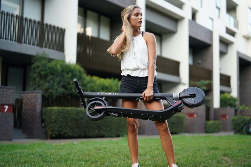 shallow focus photo of woman holding folded electric scooter