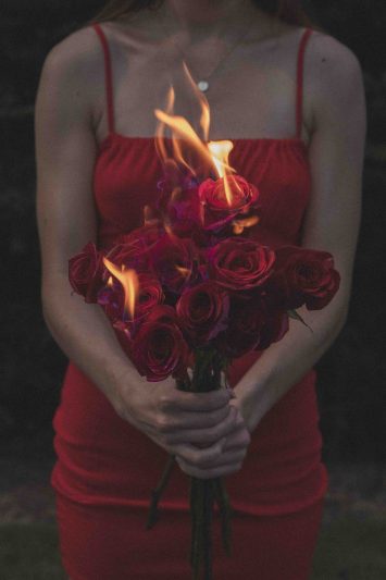 woman in a red dress holding a bouquet of burning roses