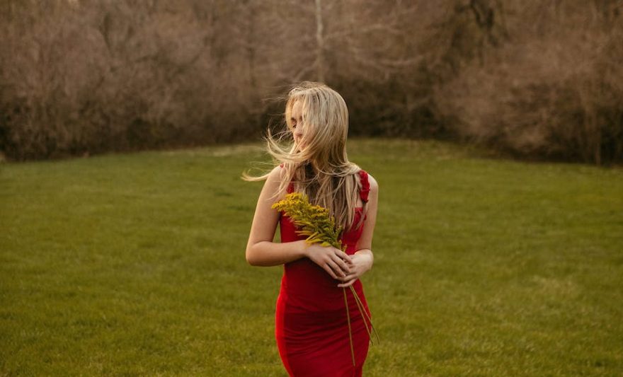 blonde girl in long red dress in spring park