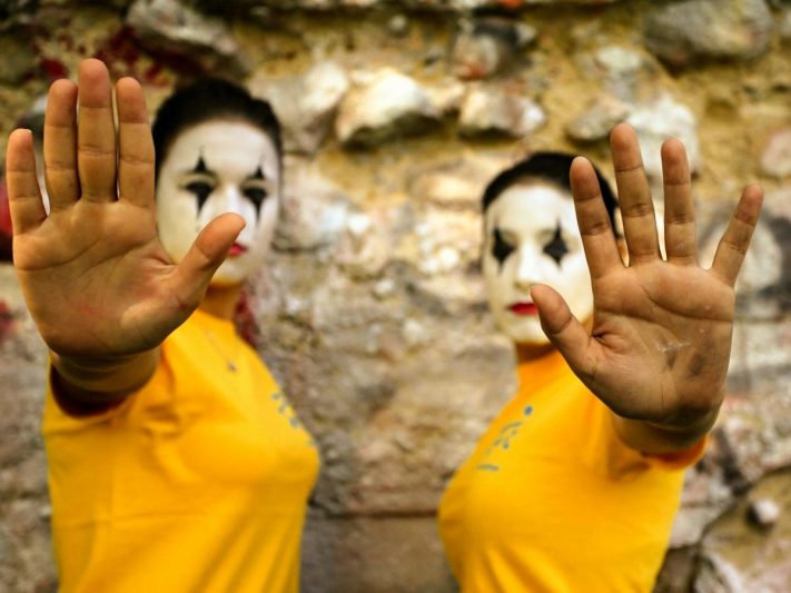 photo of two women with painted faces raising their hands in an act of objection