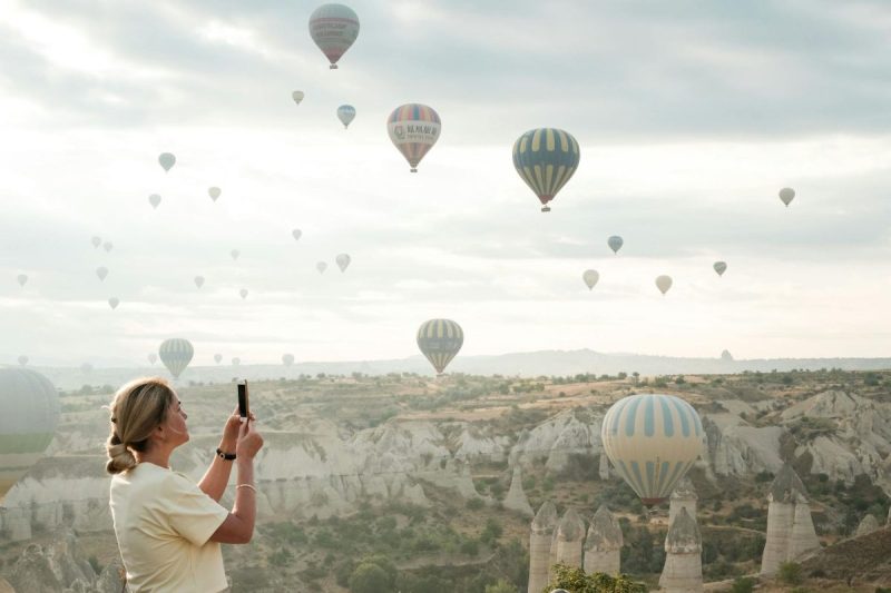 woman taking photo of hot air balloons in cappadocia