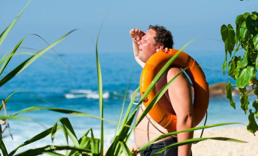 orange safety ring on man shoulder near body of water