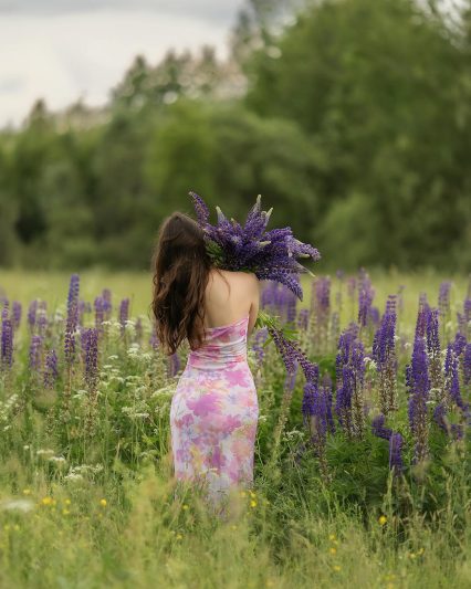 back view of woman standing and holding flowers at meadow