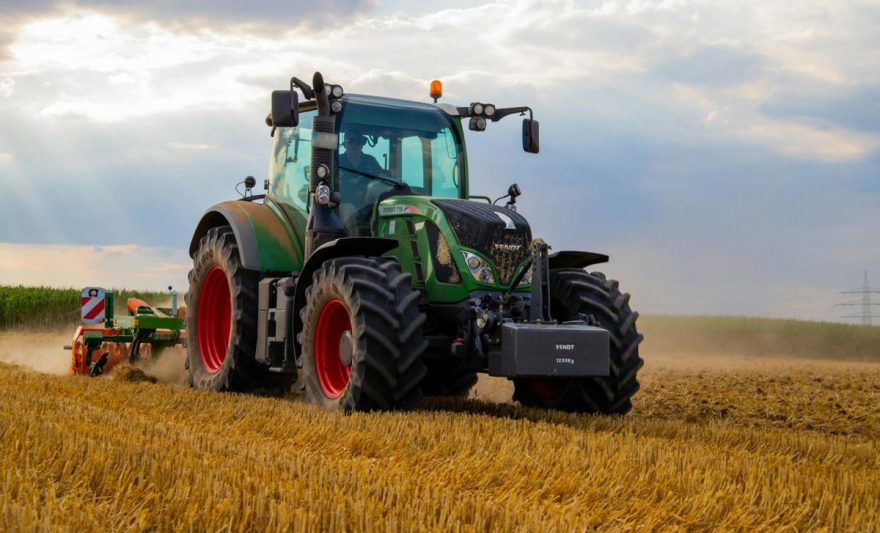 green tractor plowing the fields on focus photography