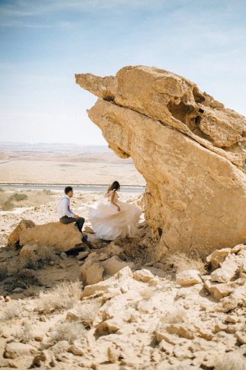 man and woman sitting beside a rock formation