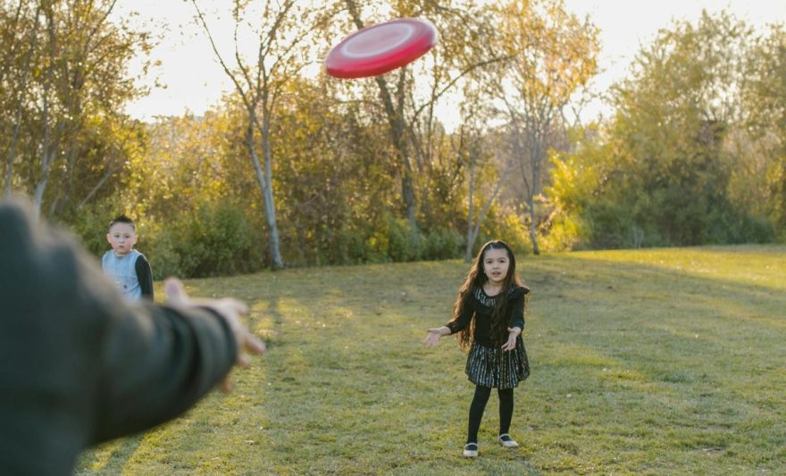 girl in black dress catching flying disc