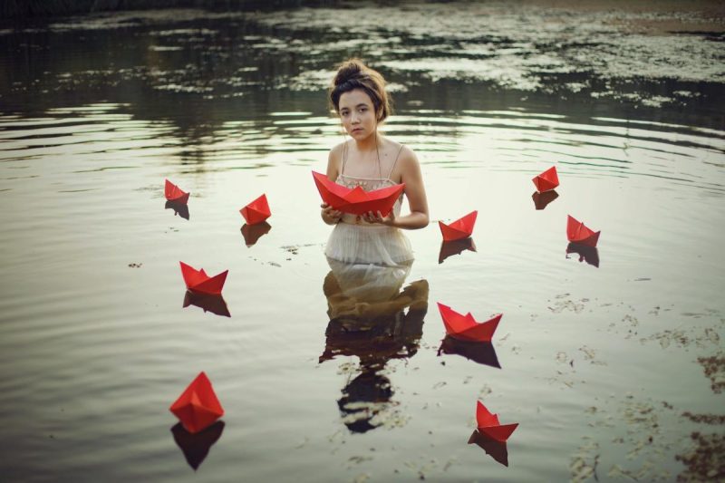 woman in water with paper ships