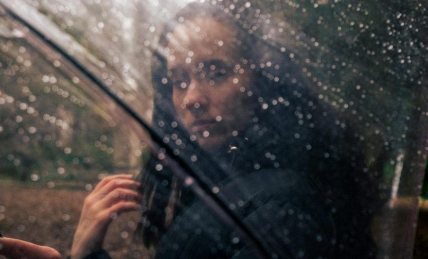 photo of a woman standing behind a transparent umbrella