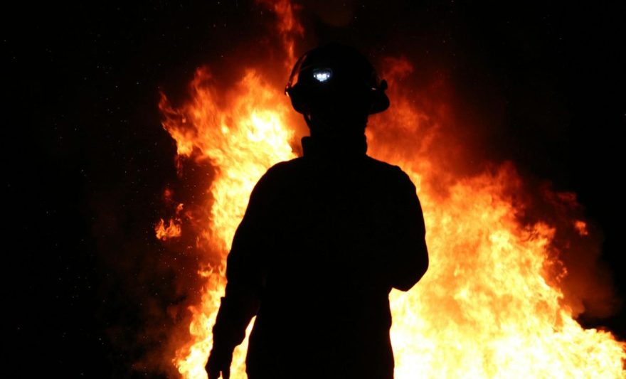 silhouette of a fireman with a fire behind his back