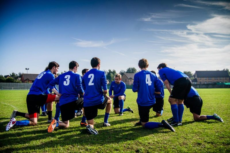 group of sports player kneeling on field