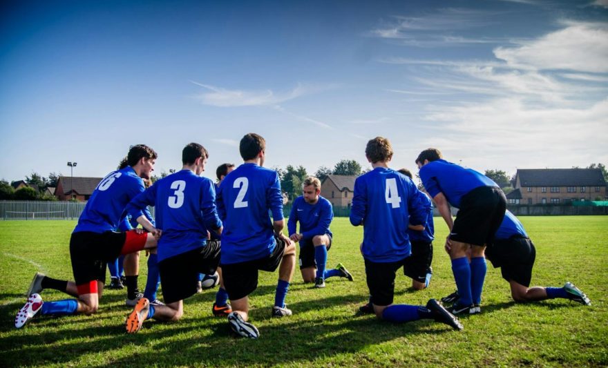 group of sports player kneeling on field