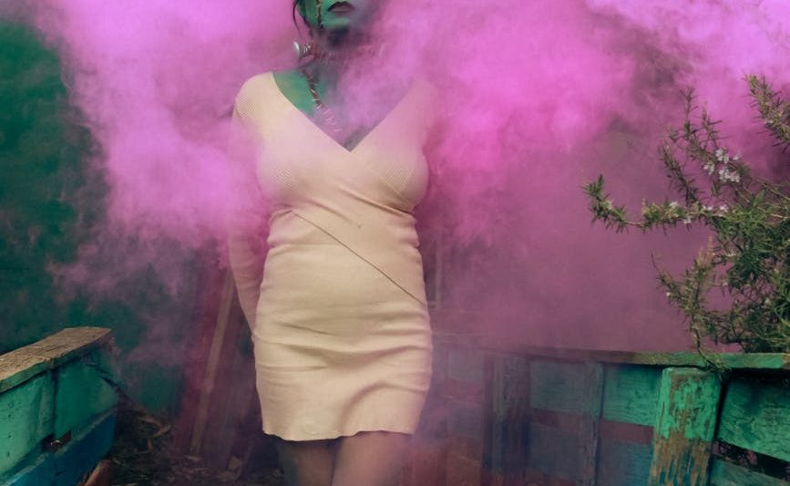 mystical woman with pink smoke in artistic setting