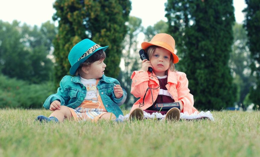 two toddlers sitting on grass field