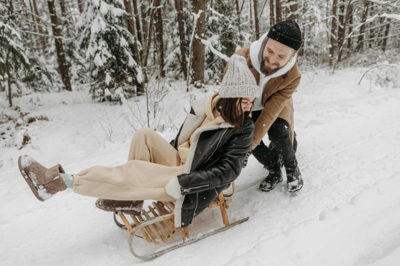 photograph of a man pushing a woman on a sled