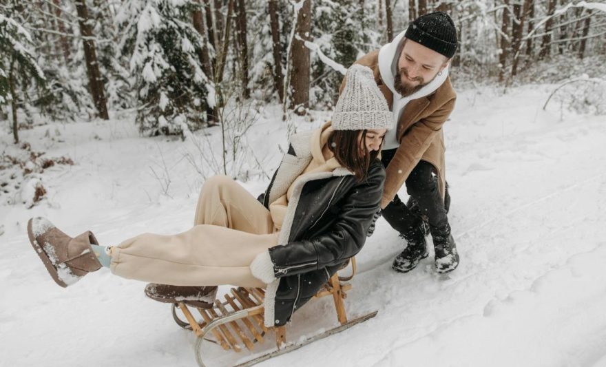 photograph of a man pushing a woman on a sled