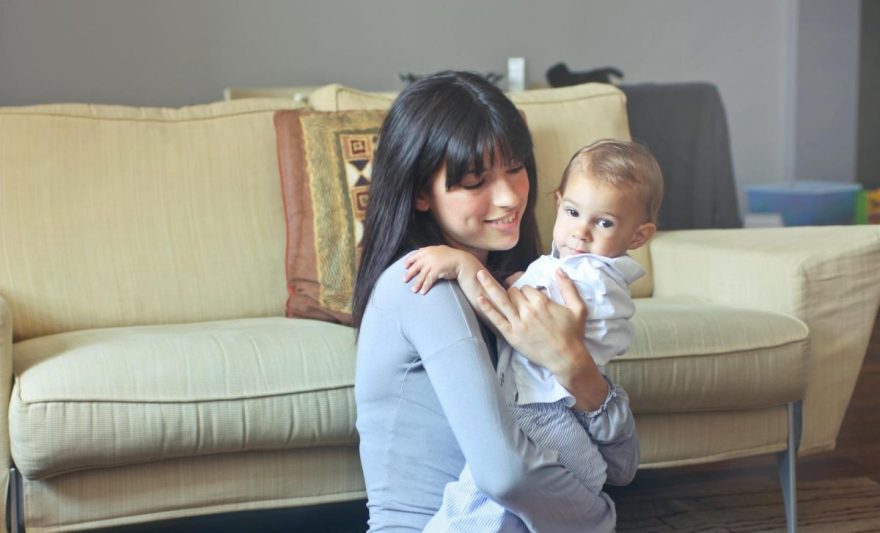 woman in gray sweater carrying toddler in white button up shirt