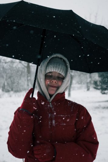 woman in red jacket holding an umbrella during snow fall