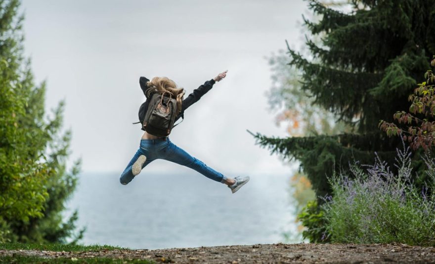 woman jumping wearing green backpack