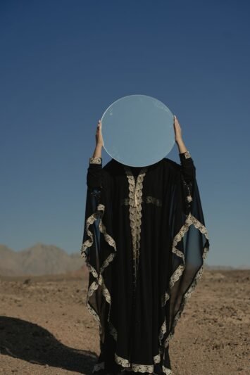 a woman wearing a black robe holding a mirror