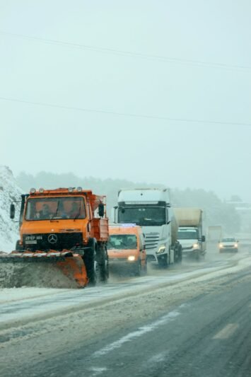 snow plow clearing road amidst winter traffic