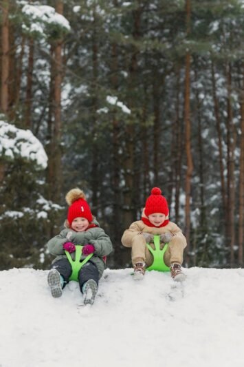 two children sitting on sleds in the snow