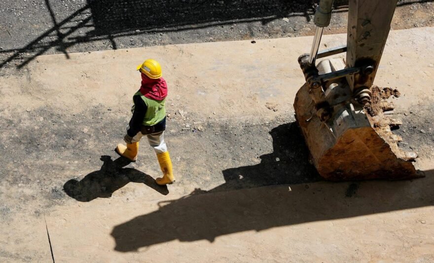 high angle photo of person walking near backhoe