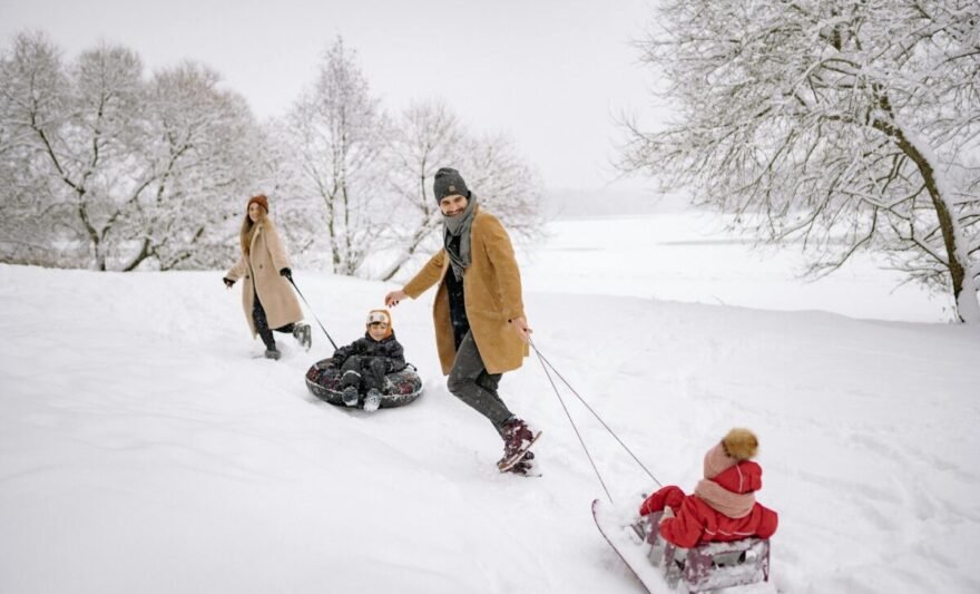 a man and a woman pulling sled on the snow with their children