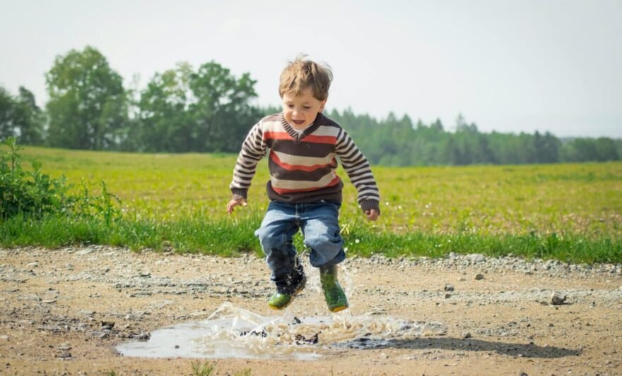 boy jumping near grass at daytime