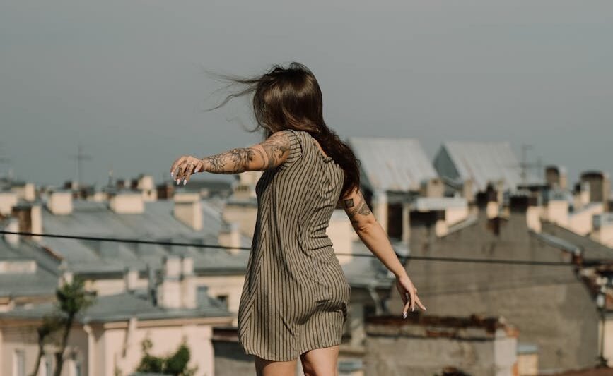 woman in gray and white stripe dress standing on brown wooden dock