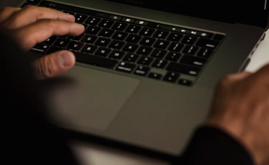 crop hacker typing on laptop with data on screen