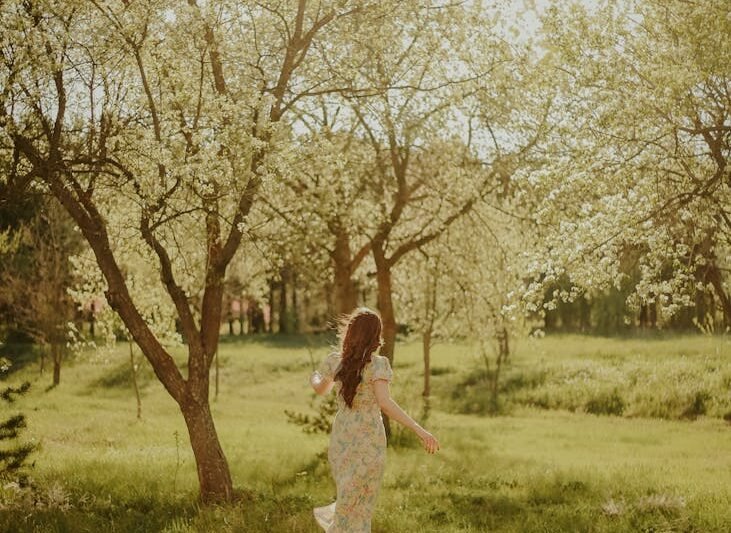 woman walking among trees in blossom at spring time
