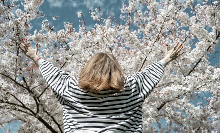 woman in striped shirt reaching up to the sky