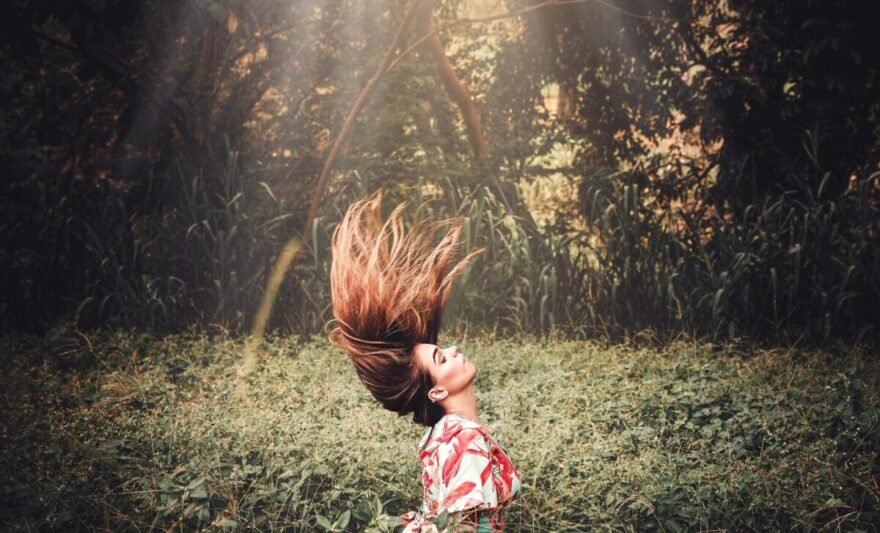 a woman flipping her hair while standing in the forest