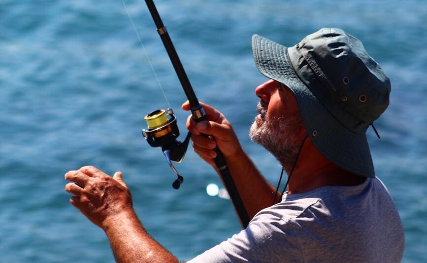 man in hat fishing with rod