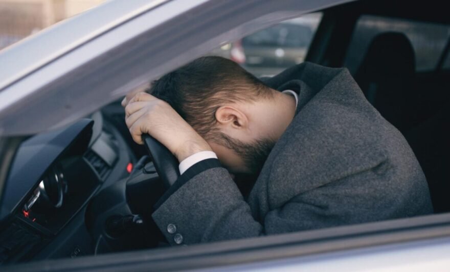 stressed man in car resting on steering wheel