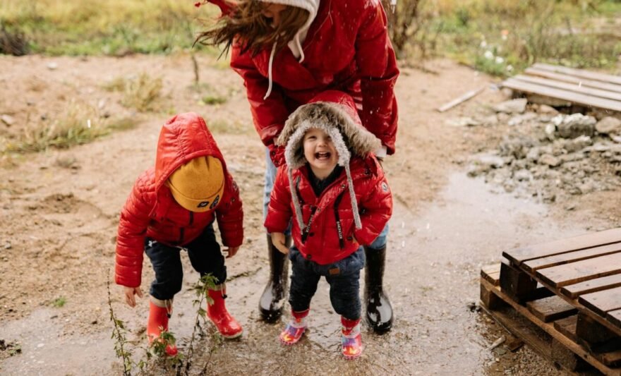 a mother and her children jumping on a puddle