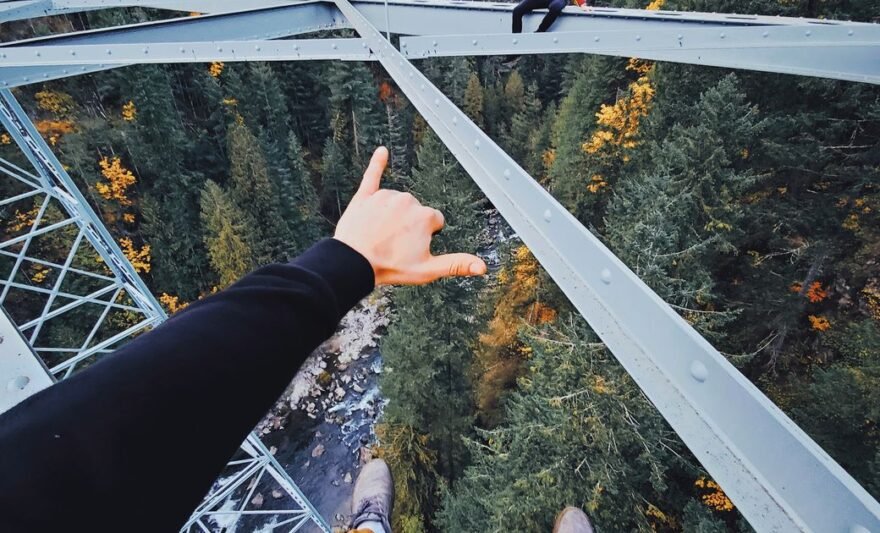 person in black pants and brown shoes standing on white metal bridge