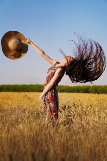 woman in red and green floral dress standing on wheat field
