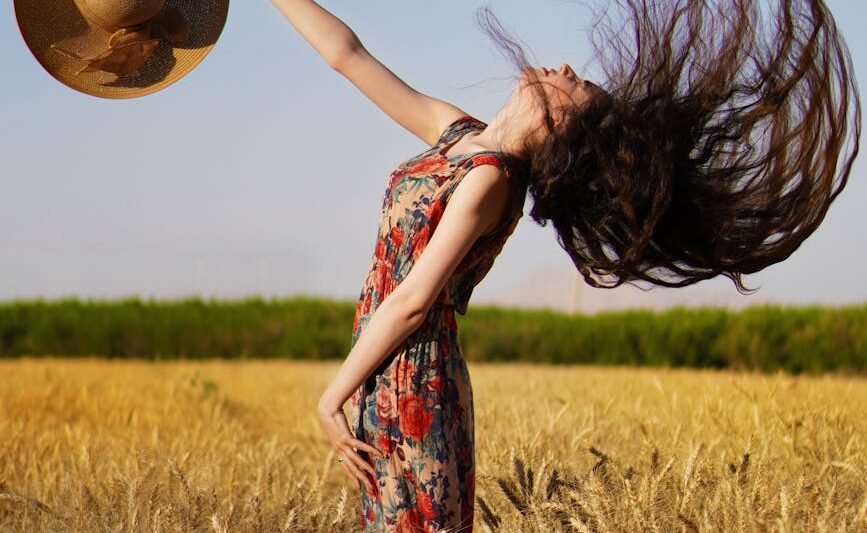 woman in red and green floral dress standing on wheat field
