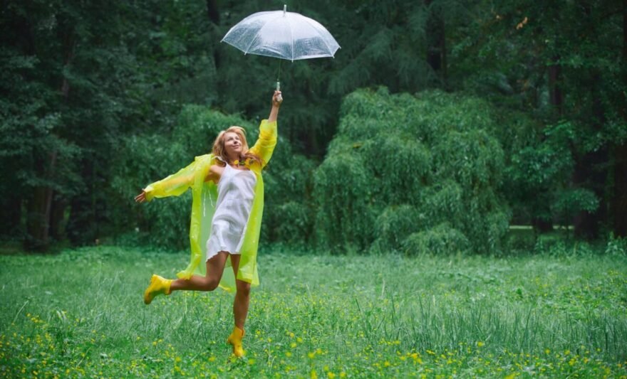 joyful woman in rainy park with umbrella