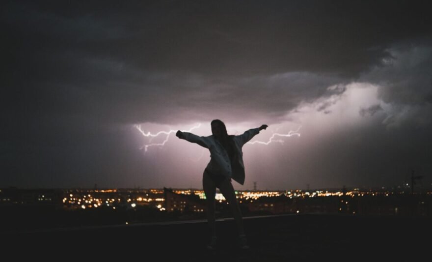 silhouette of a woman posing against a thunderstorm at night