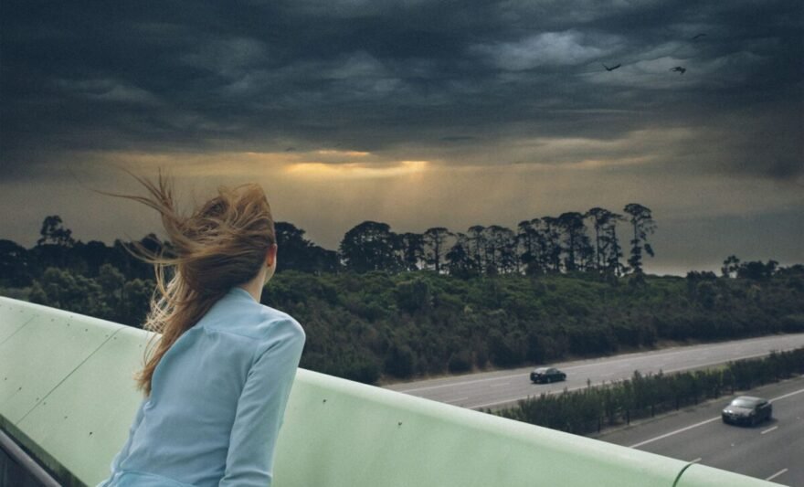 brunette woman on bridge looking at storm clouds