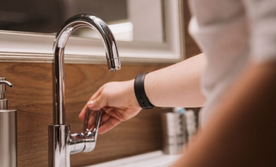 a person turning a faucet handle